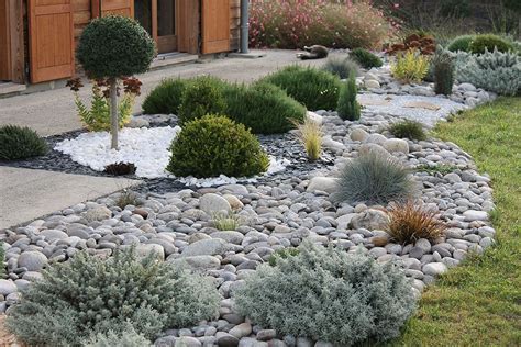Exemple de jardin minéral avec du gravier blanc, des pierres et des graminées.