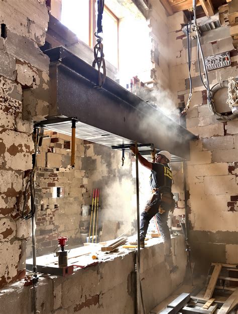 Ouvrier installant des étais sous un mur porteur