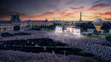 Scène de concert en extérieur avec des artistes jouant de la musique, public attentif.