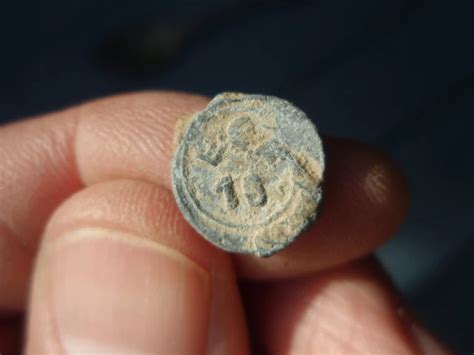 Gros plan sur un plomb de scellé avec des inscriptions et des symboles