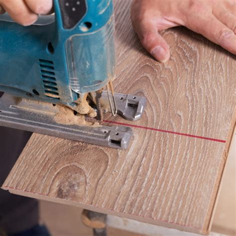 Scie sauteuse coupant une lame de parquet stratifié