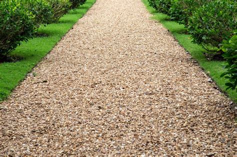 Vue rapprochée d'un râteau étalant du gravier sur une allée