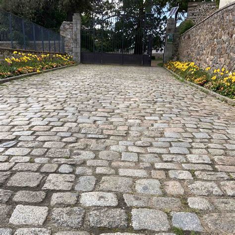 Vue d'ensemble d'une allée en pavés de granit avec un caniveau.