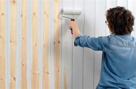 Peintre appliquant de la peinture sur un mur en lambris