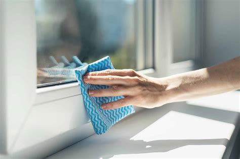Personne nettoyant une fenêtre en PVC avec une éponge et un seau
