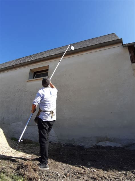 Technicien utilisant une perche carbone pour nettoyer une façade