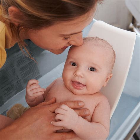 Parent donnant le bain à bébé avec un support