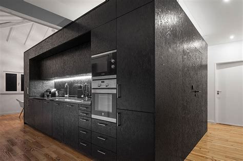 Structure cubique en OSB peint en noir abritant une cuisine et des rangements