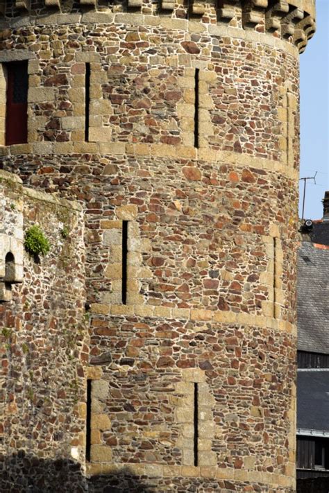 Diversité des formes de meurtrières (archères et arbalétrières) sur un mur de château