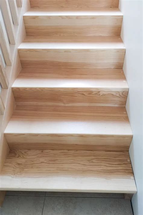 Escalier en bois avec garde-corps en frêne contre un mur en pierre