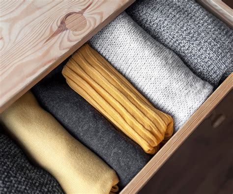 Illustration de pulls pliés verticalement dans un tiroir selon la méthode KonMari