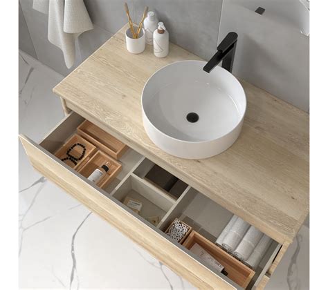 Vasque ronde rose vif avec robinetterie dorée sur un meuble en bois clair