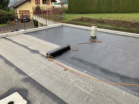 Détail de la pose de rouleaux de bitume pour l'étanchéité d'une terrasse