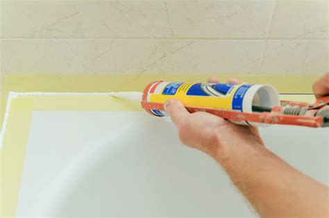 Application de silicone sanitaire sur le joint entre un receveur de douche et un mur
