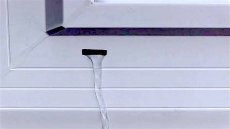 Image montrant un trou de drainage de fenêtre PVC bouché par de la saleté et de la mousse