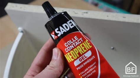 Main appliquant de la colle néoprène sur une grande surface